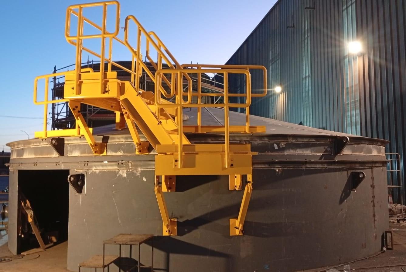 Plataforma y escalera amarillas montadas sobre el techo del estanque al atardecer